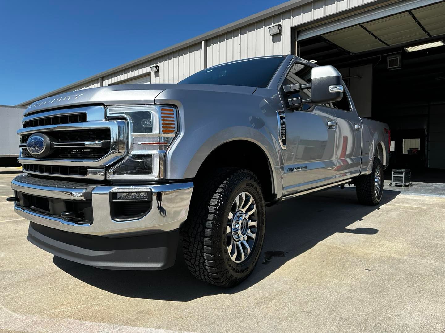A silver ford truck is parked in front of a garage.
