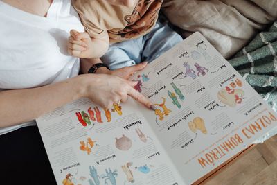 Child in a pink shirt at a table, coloring a worksheet beside a cup of crayons.