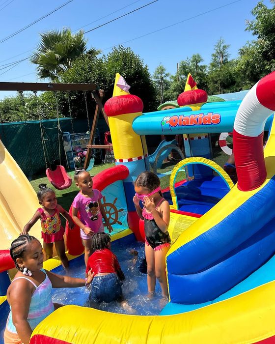 Children playing in a colorful inflatable water slide and splash pool on a sunny day