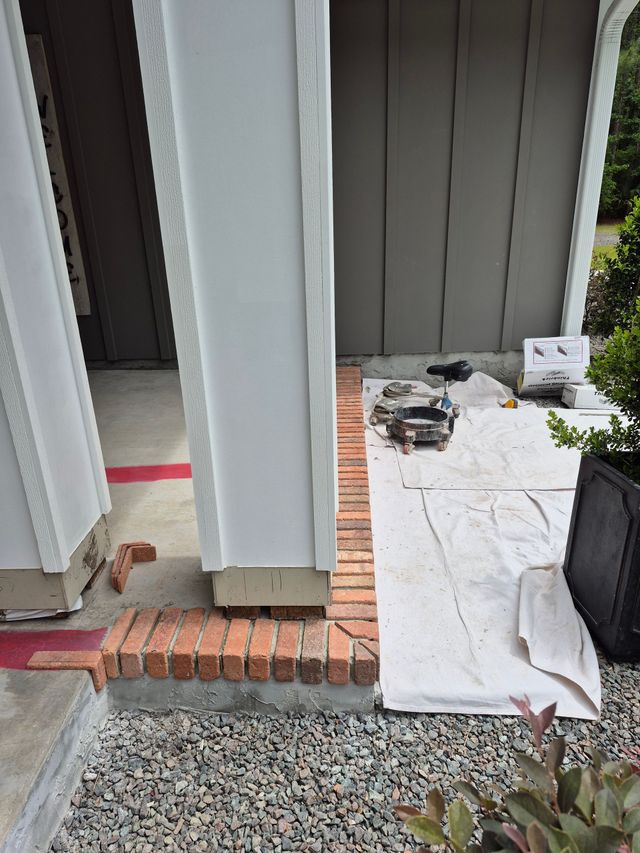 Front entrance with brick step, gravel path, and a white board walkway beside the porch.
