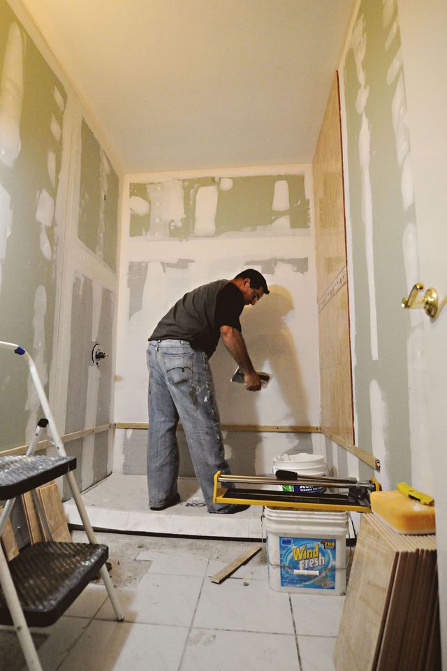 Person plastering drywall in a narrow room under renovation