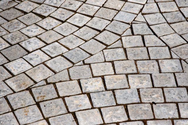 Gray cobblestone pavement with irregular stone tiles and grout lines