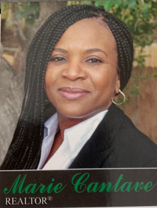 Portrait of realtor Marie Cantave in a black blazer and white shirt, with braided hair, smiling outdoors