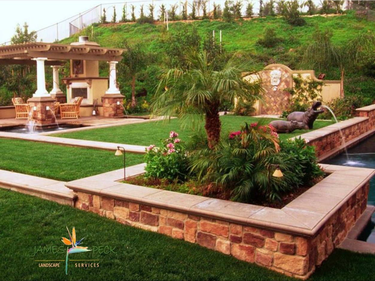 Luxurious backyard with a pool, lawn, fountain, stone structures, and hillside.
