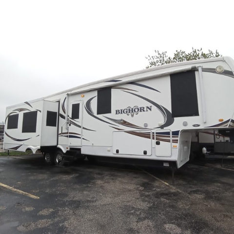 A white bighorn rv is parked in a parking lot