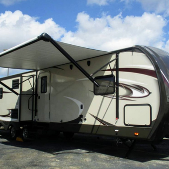 A rv with a canopy is parked in a parking lot