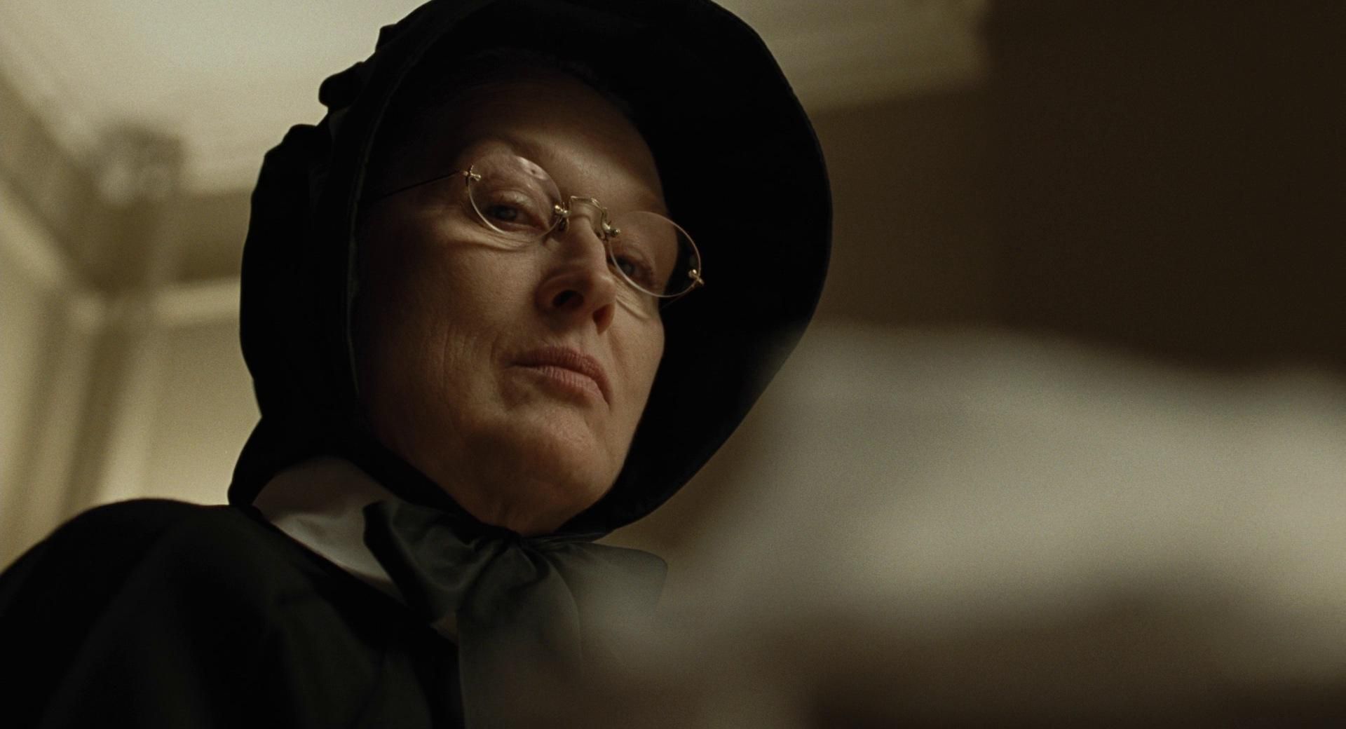 Contra-plongée Low-angle portrait of a person in a black hat and glasses, looking sternly into the distance