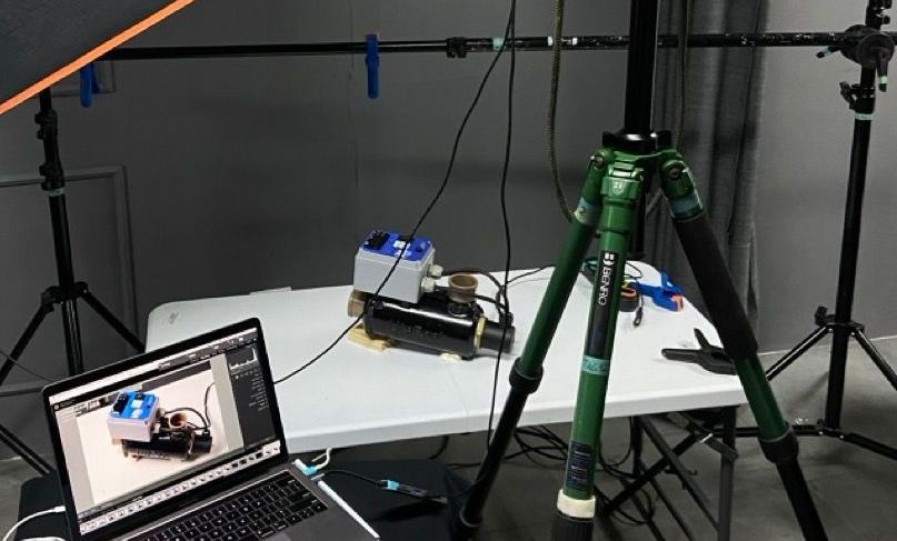 Um laptop está sobre uma mesa ao lado de um tripé.
