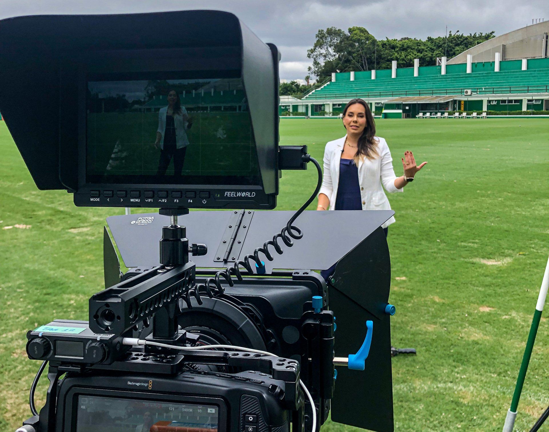 Uma mulher está diante de uma câmera em um campo.