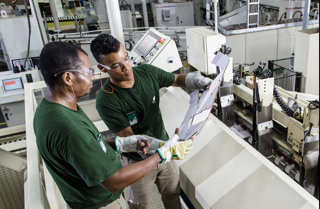 Dois homens estão trabalhando em uma máquina em uma fábrica