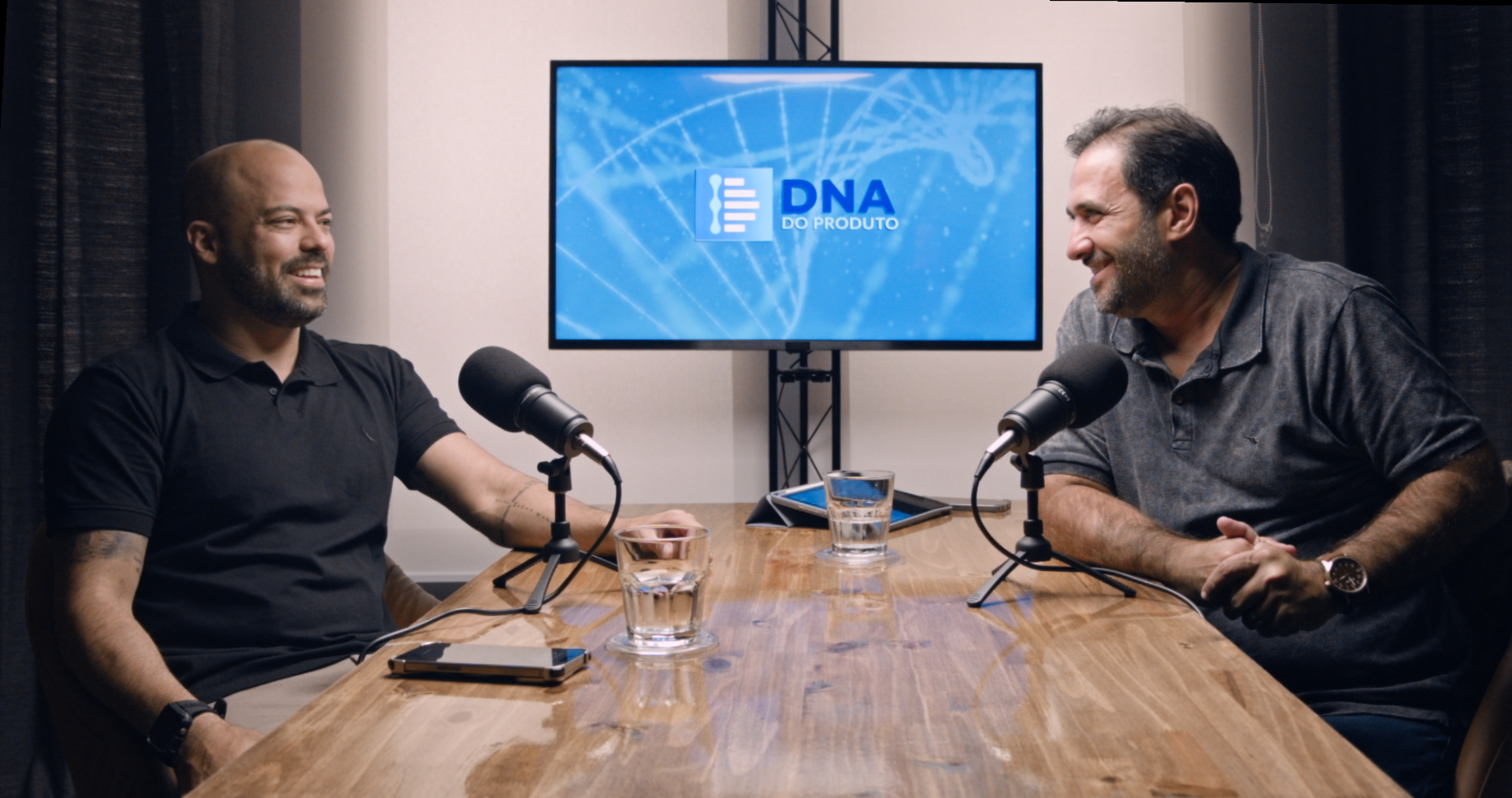 Gravamos e editamos o podcast da sua empresa Um grupo de pessoas está sentado em uma mesa em frente a microfones.