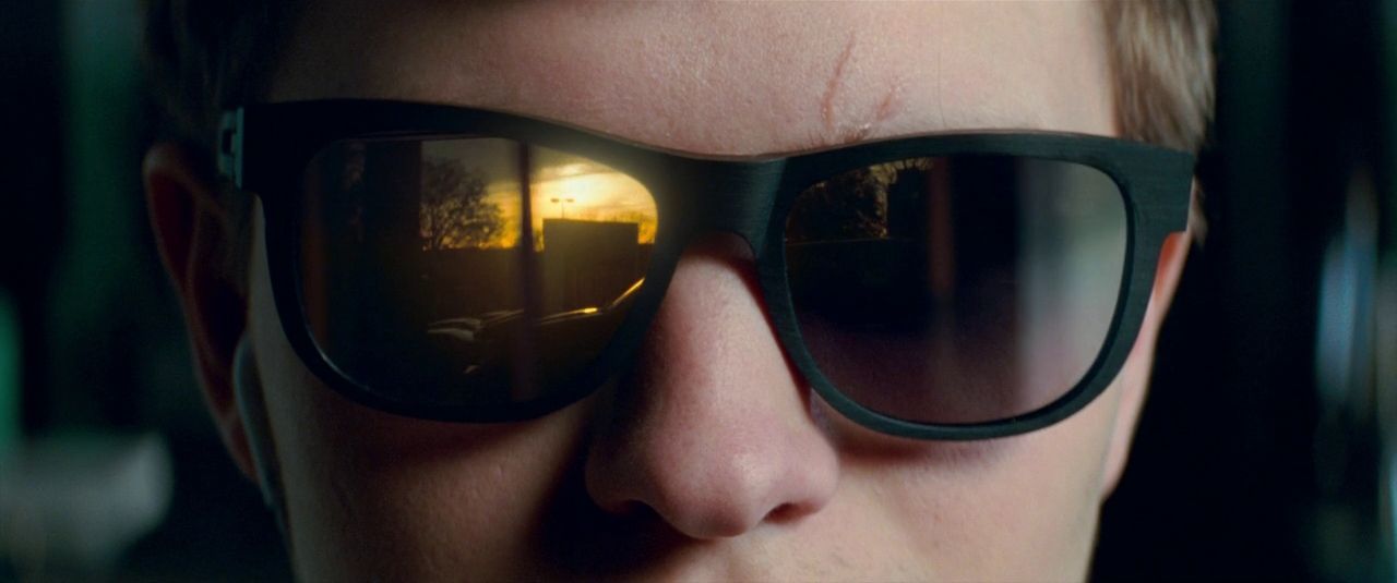 Primeiríssimo plano Close-up of a person wearing black sunglasses reflecting warm light