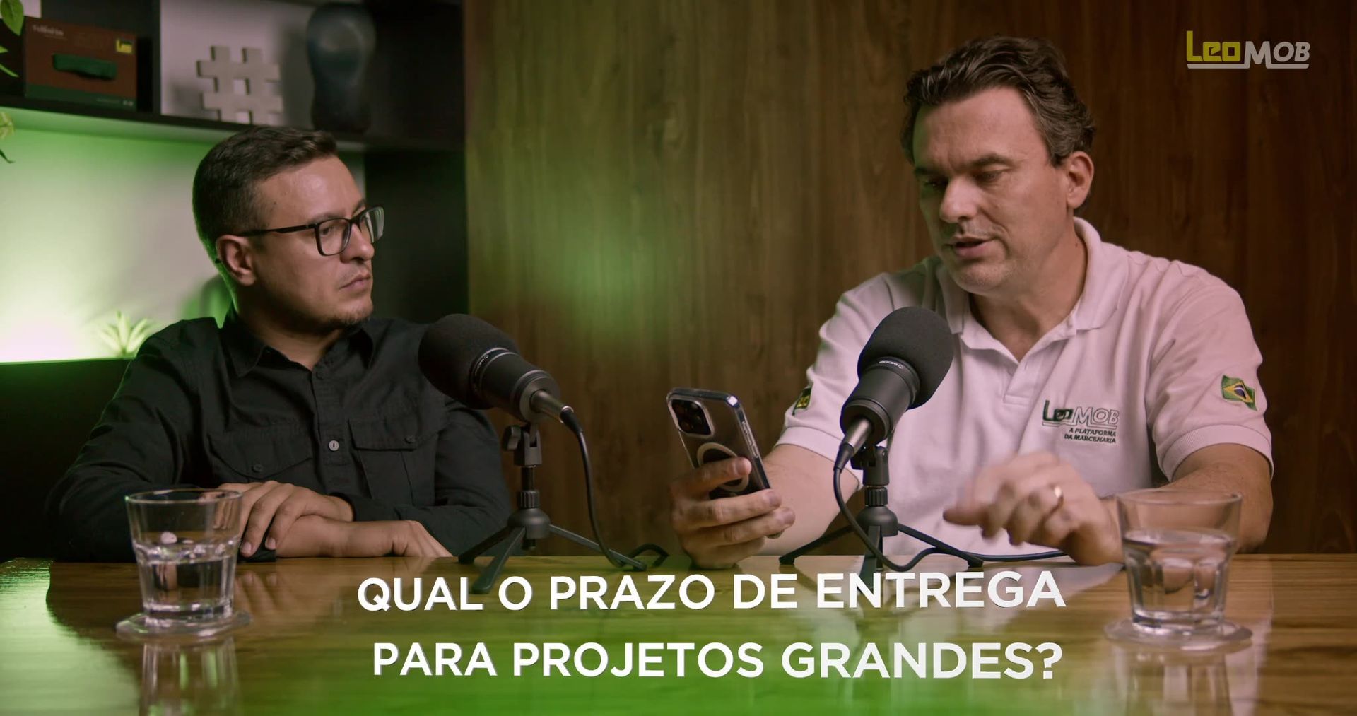 Gravação do Treinamento LeoMob Dois homens estão sentados à mesa falando em microfones.