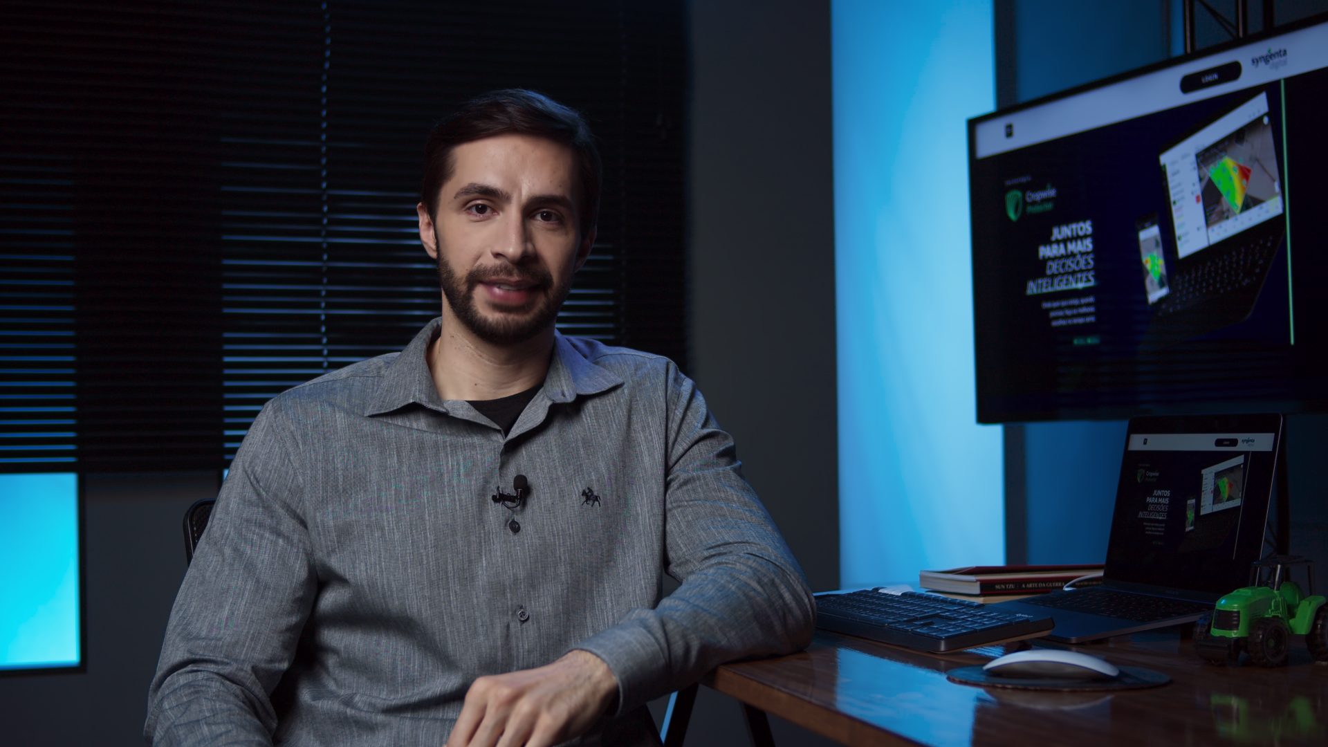 Um homem está sentado em uma mesa em frente a um monitor de computador.