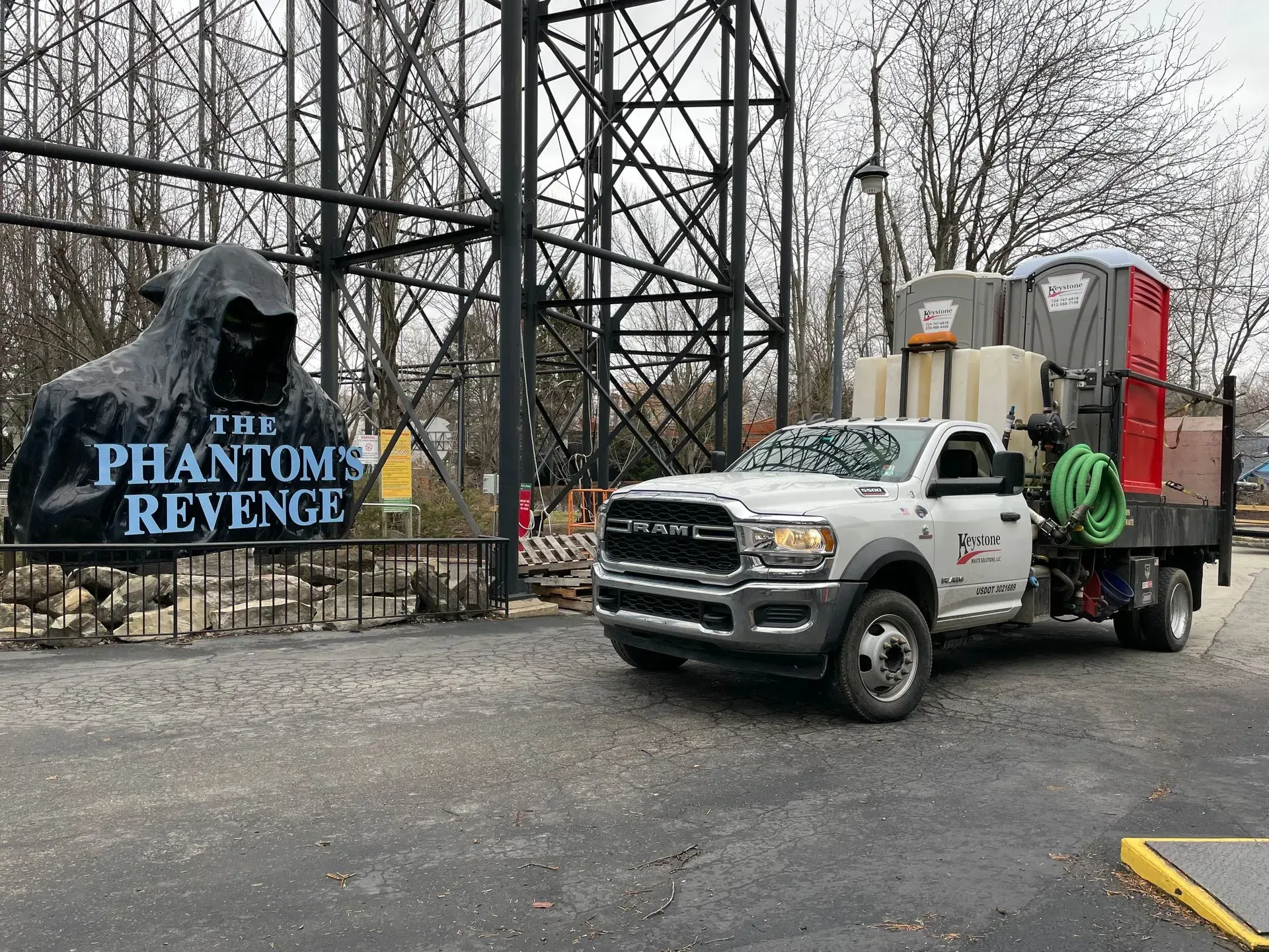 A white truck is parked in front of a sign for the phantom's revenge.
