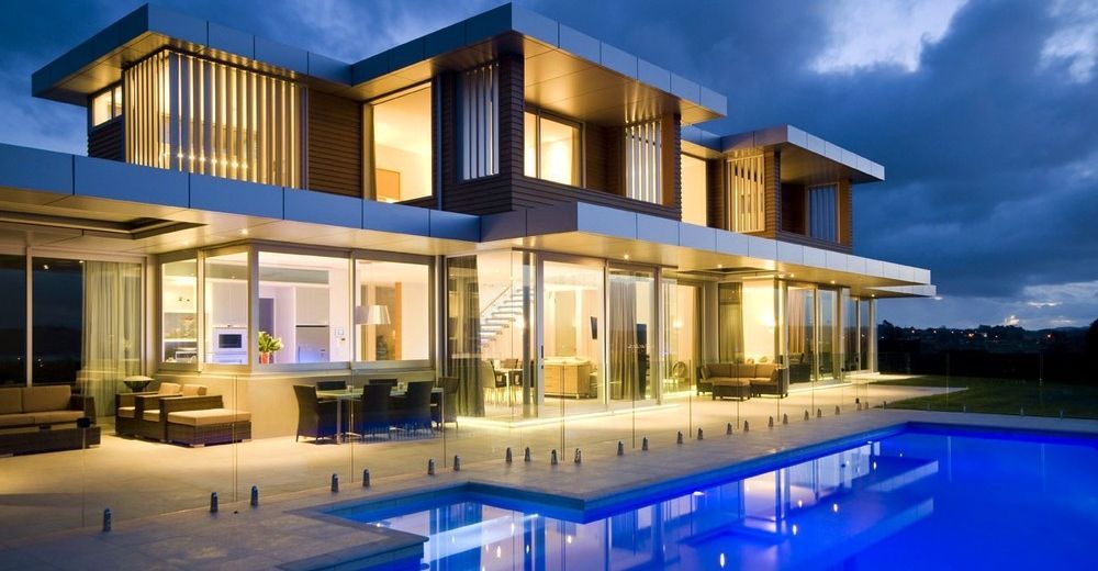 Modern luxury home with a pool illuminated at dusk.