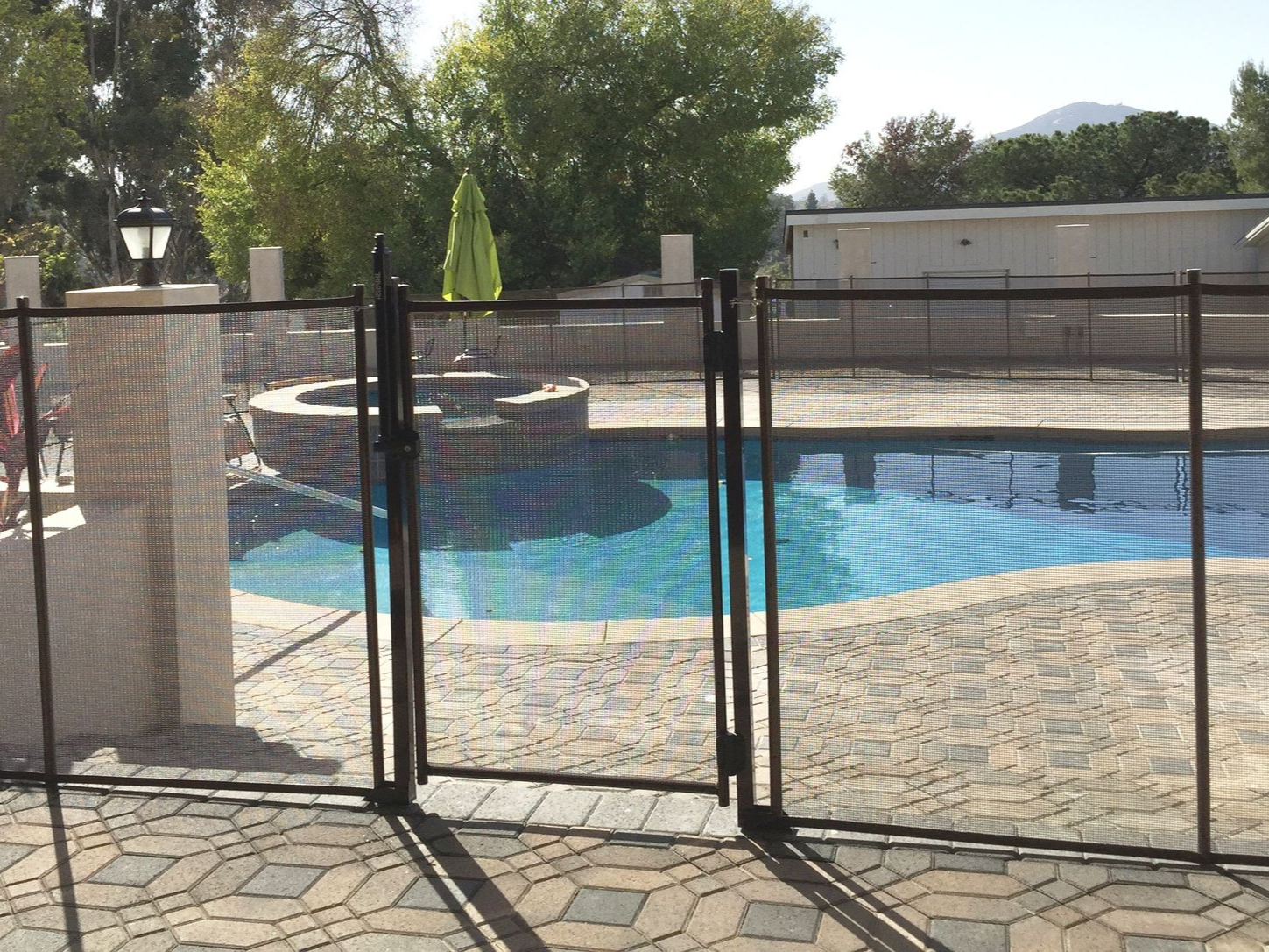 Black mesh pool fence with two gates protecting a pool.