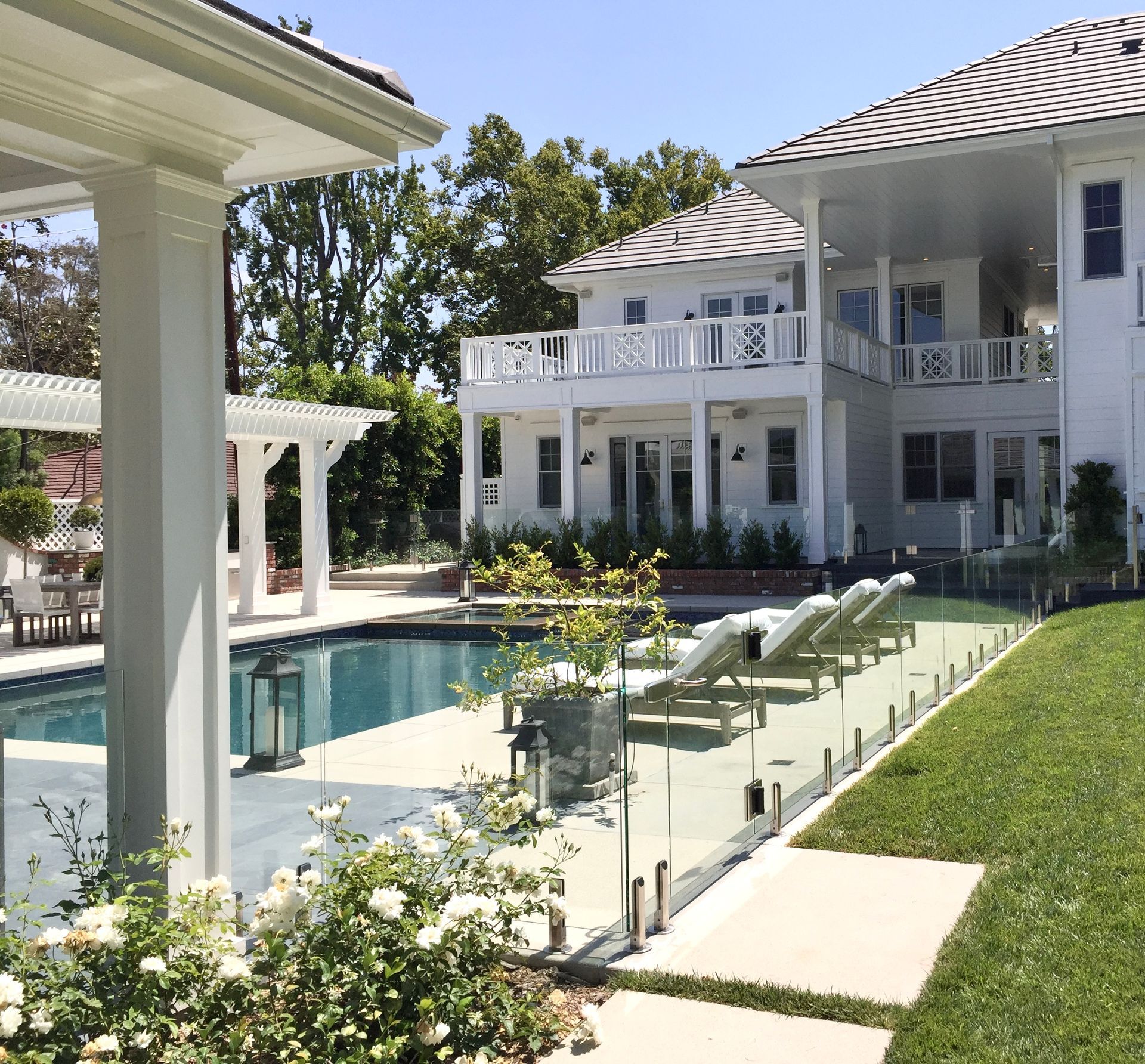 image of a white home in California's backyard that includes a pool and a glass fence around it