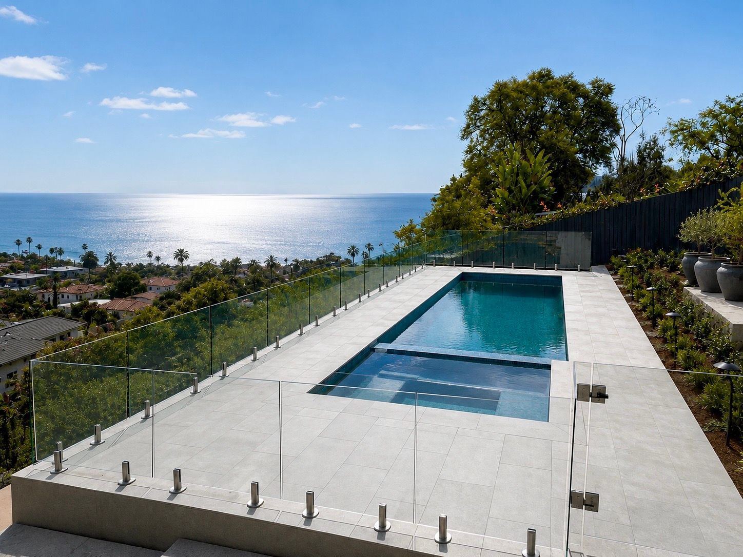 Image of a residential home in California overlooking the ocean that includes a pool and a glass fence around it