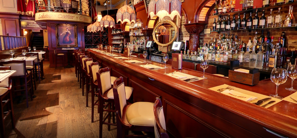 A long wooden bar in a restaurant with a lot of bottles on it.