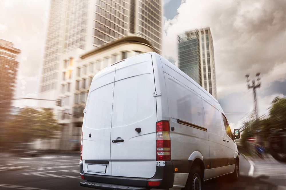 A White Van Is Driving Down A City Street — Express City Couriers in Cairns, QLD