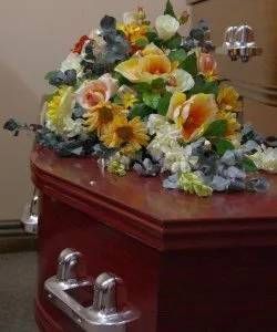 A coffin with flowers on top of it in a room.