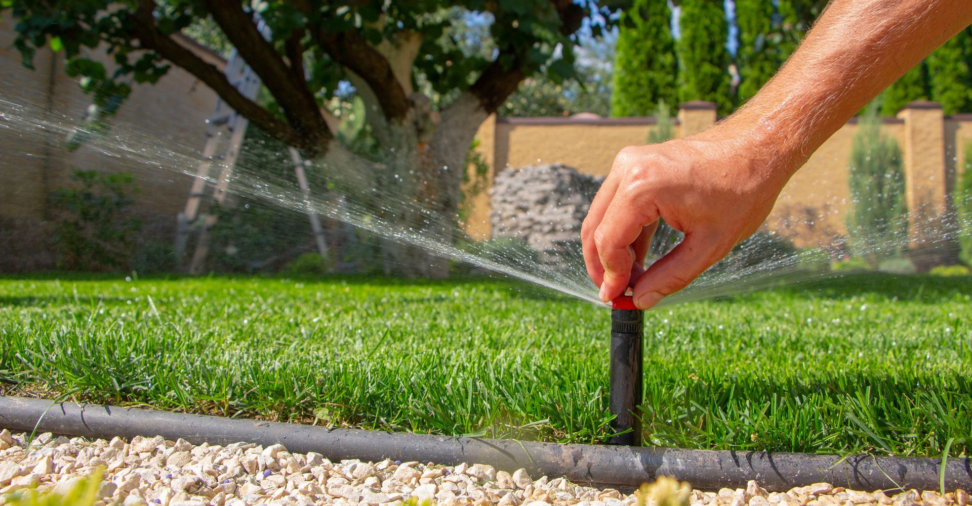 A contractor's hand manipulating irrigation system on a background of green grass. A contractor's hand manipulating irrigation system on a background of green grass.