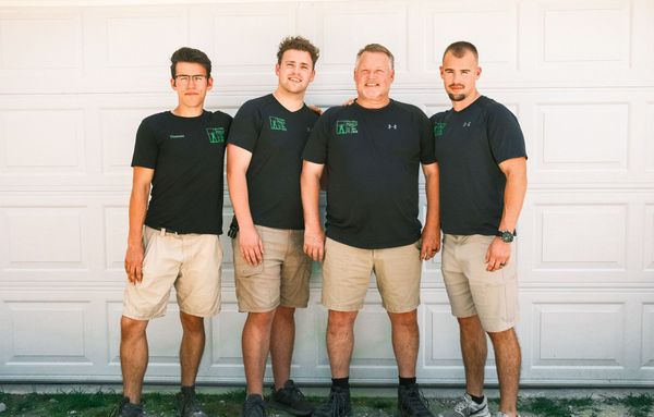 A group of men are posing for a picture in front of a garage door.