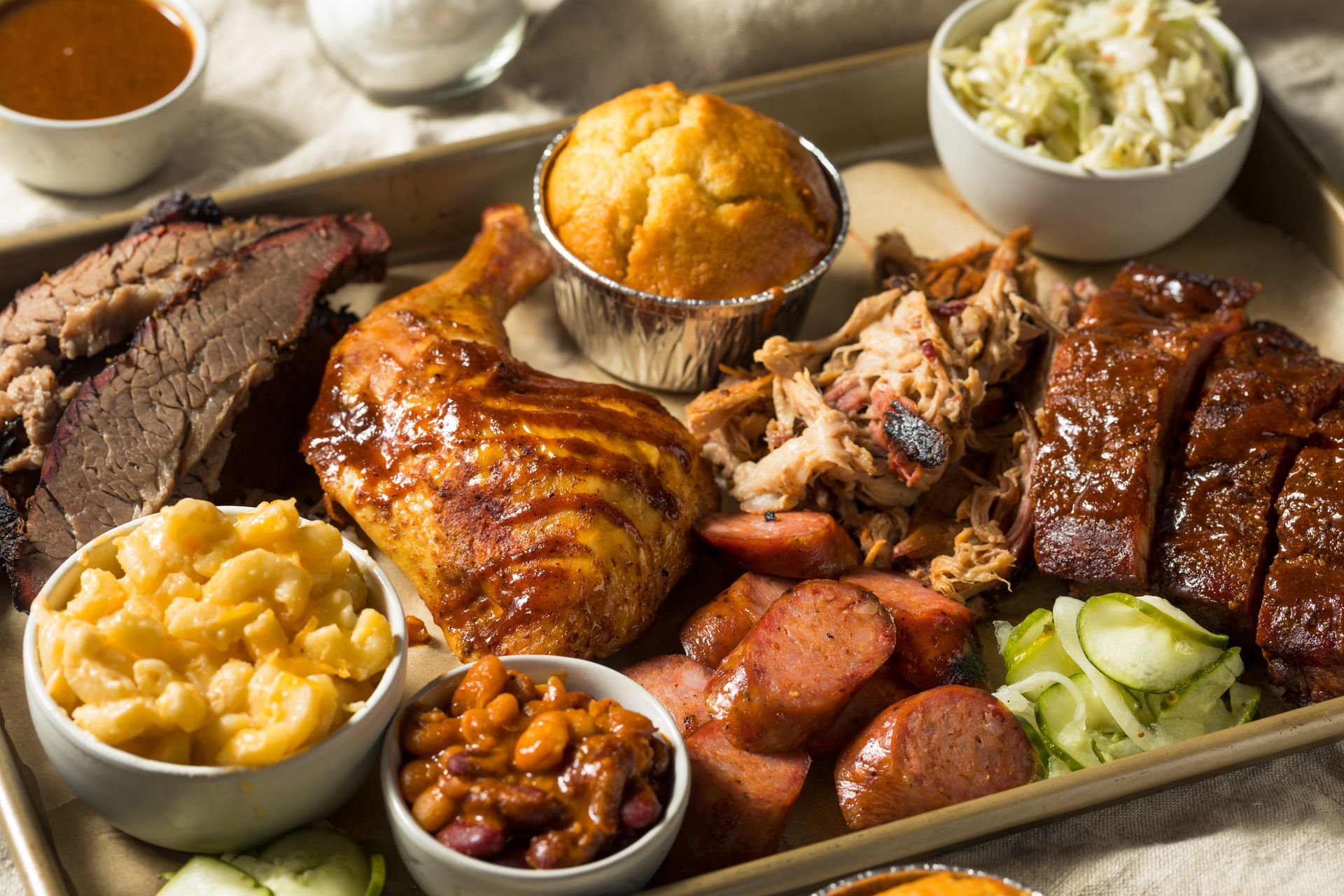 Barbecue platter with brisket, chicken, ribs, baked beans, mashed potatoes, coleslaw, and cornbread