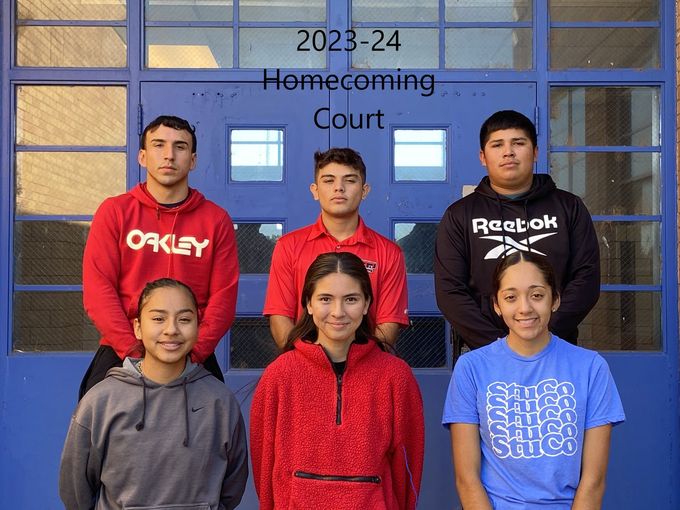 a group of young people are posing for a picture in front of a blue building .
