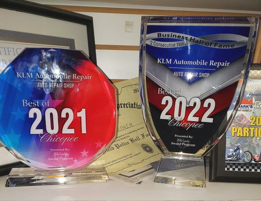 Two automotive repair awards: red 2021 plaque and silver 2022 plaque on a shelf.