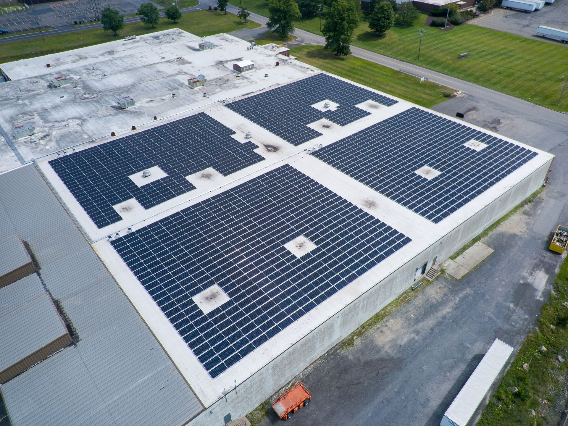 Aerial view of a commercial building roof with large, rectangular arrays of black solar panels installed.