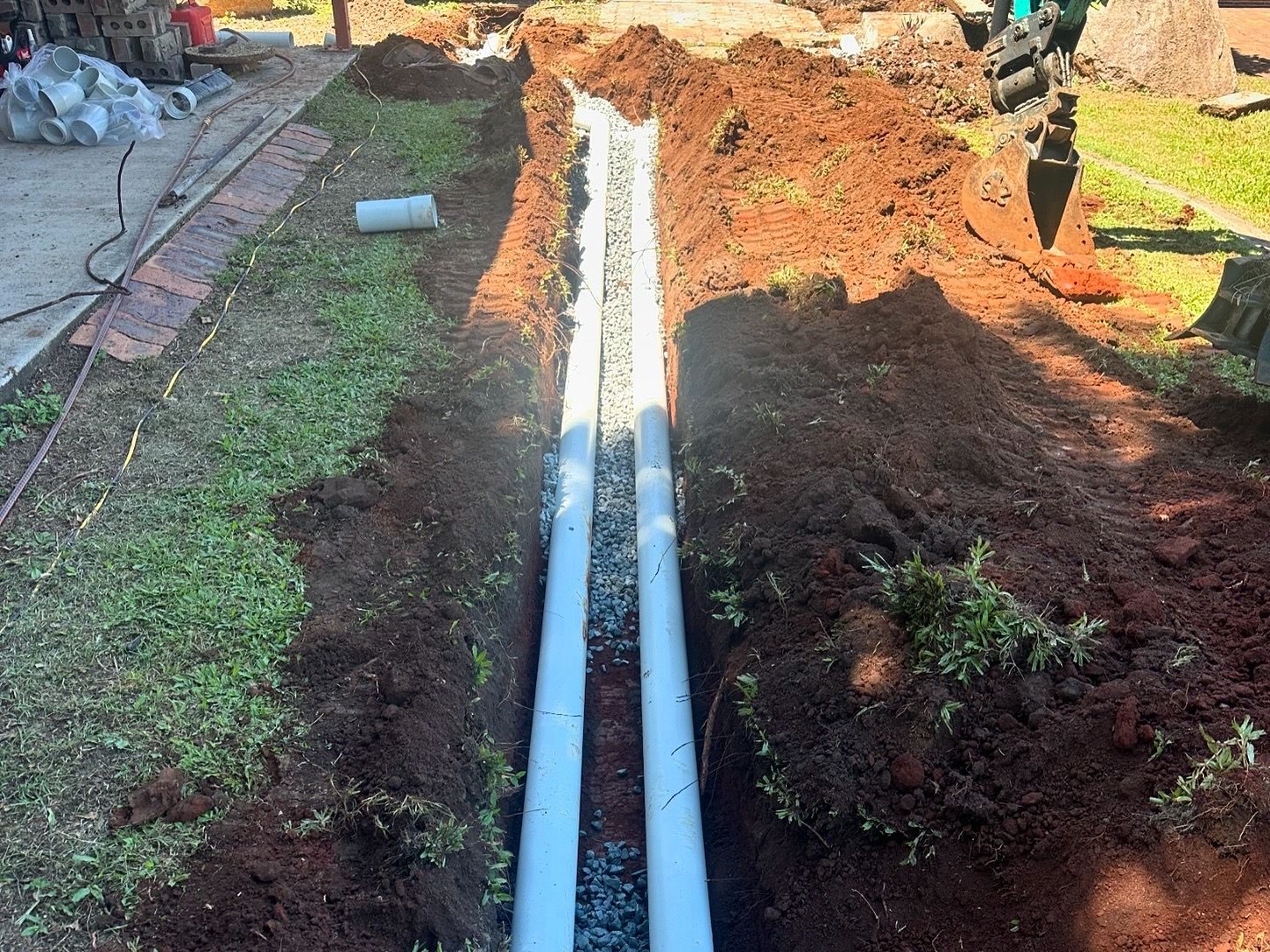 Two White Pipes Are Being Installed Under The Ground — Otto’s Plumbing & Gasfitting in McDowall, QLD