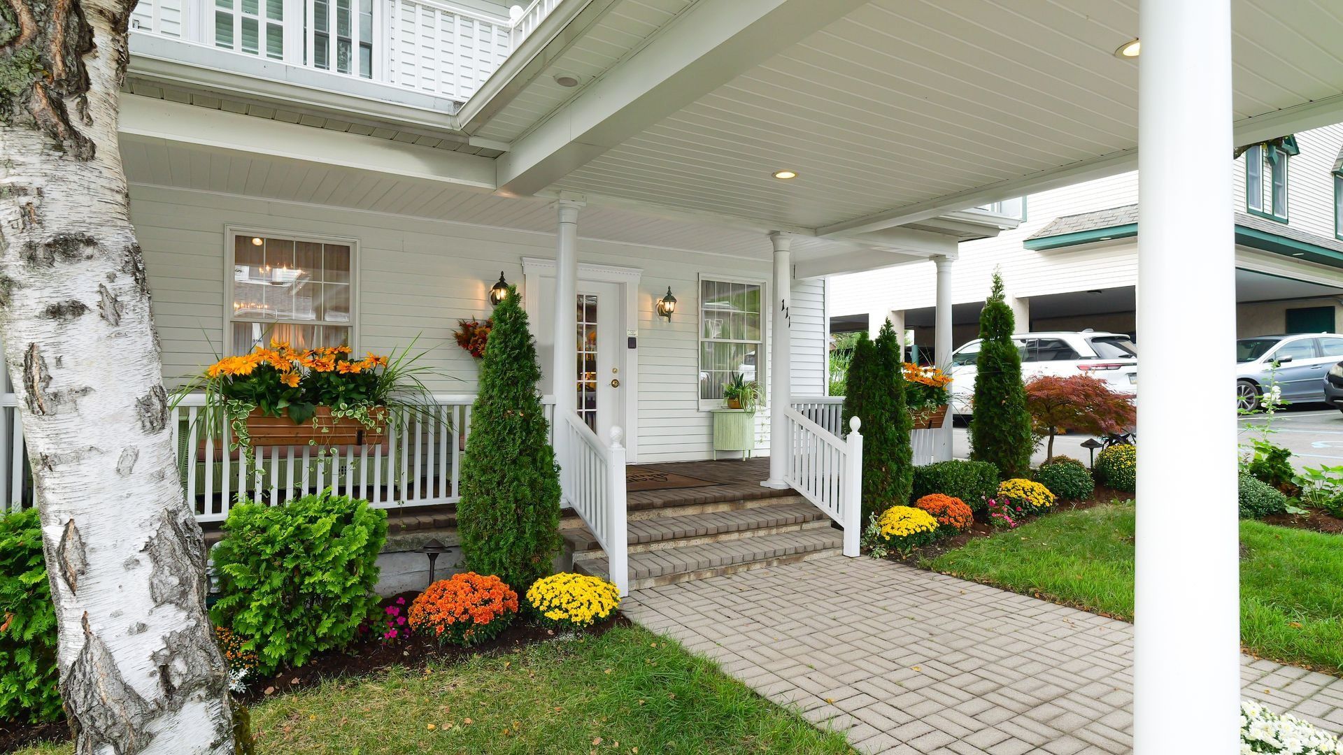 front porch of jennings calvey funeral home in clarks summit pa with yellow and orange flowers in the garden