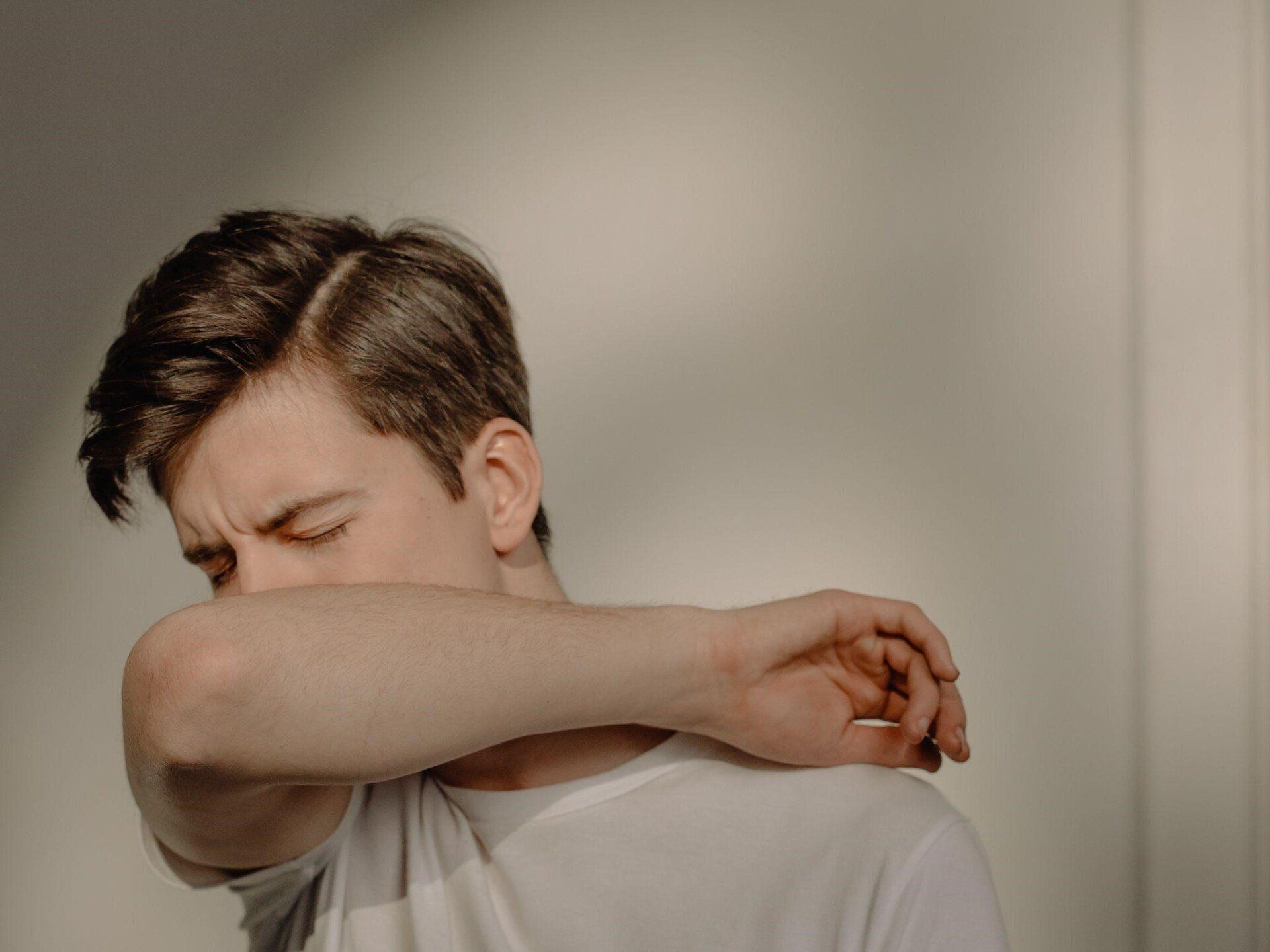 A man sneezing in his elbow