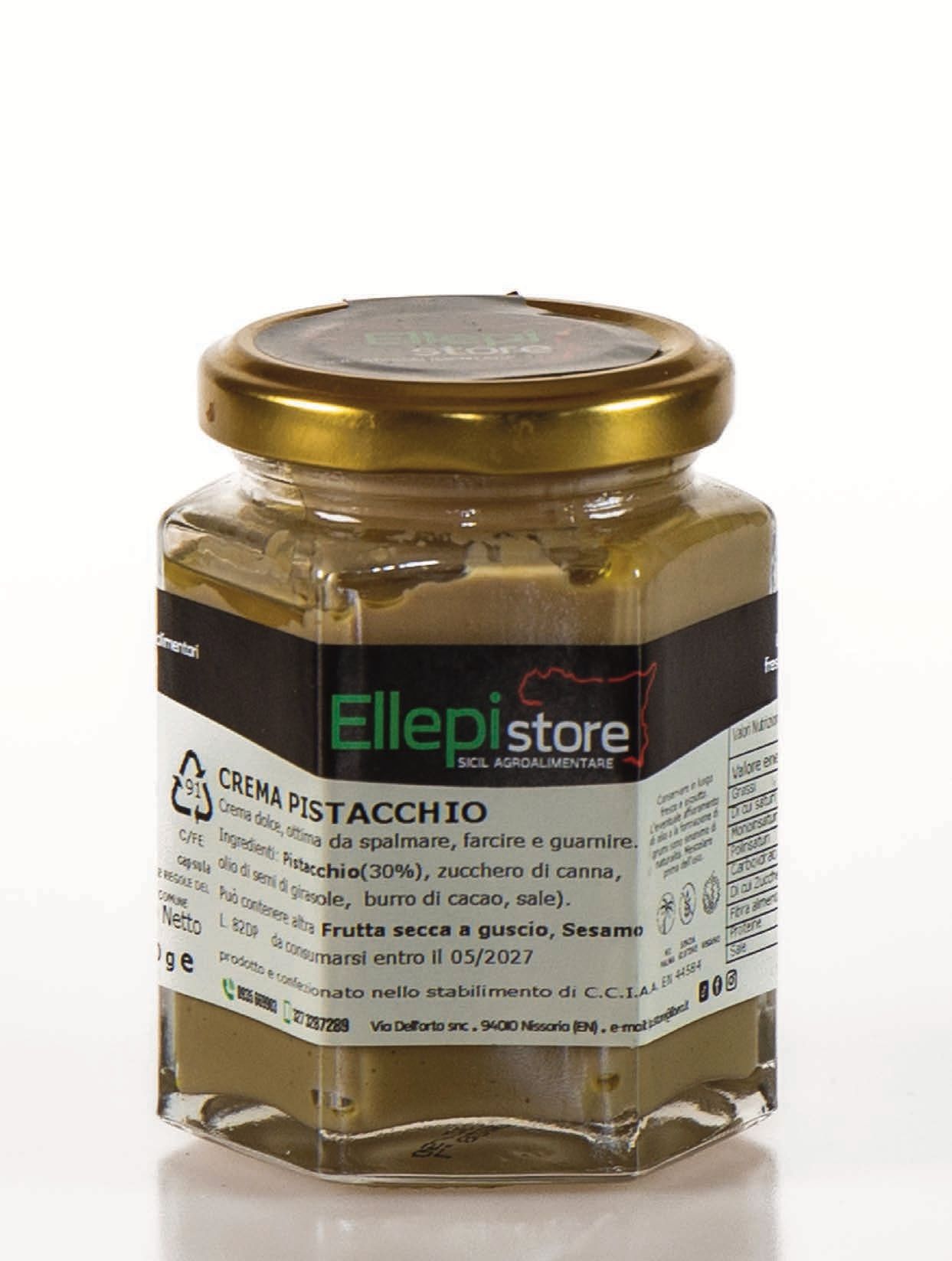 Un barattolo di crema al pistacchio è appoggiato su una superficie bianca.