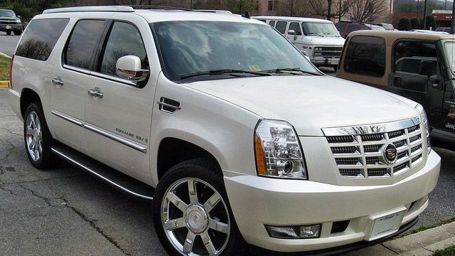 White Cadillac Escalade SUV parked outdoors in a lot, front-left view