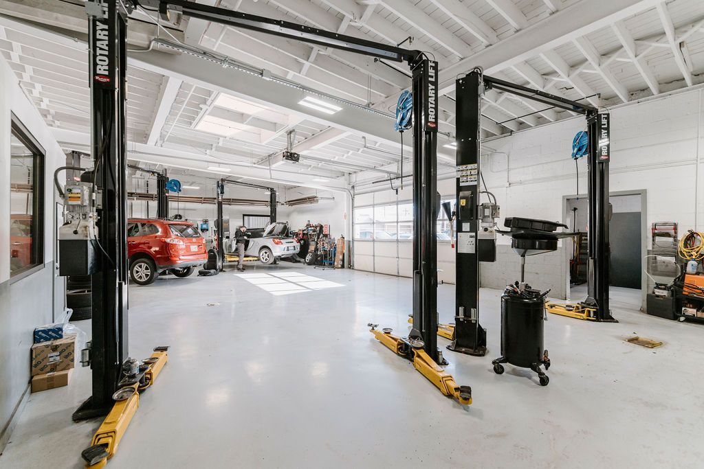 Bright auto repair garage with car lifts, tools, and a red vehicle inside