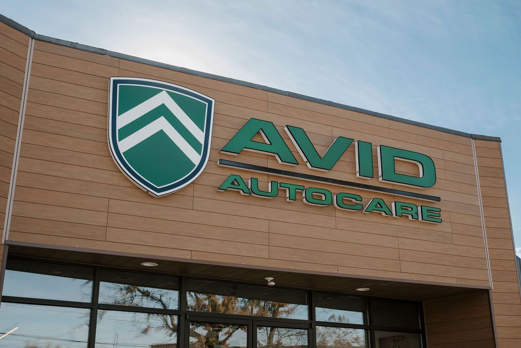 AVID AutoCare storefront sign on a brick building with a green shield logo.