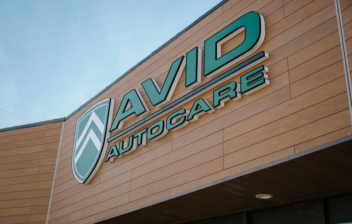 AVID AutoCare sign on a tan building exterior against a blue sky