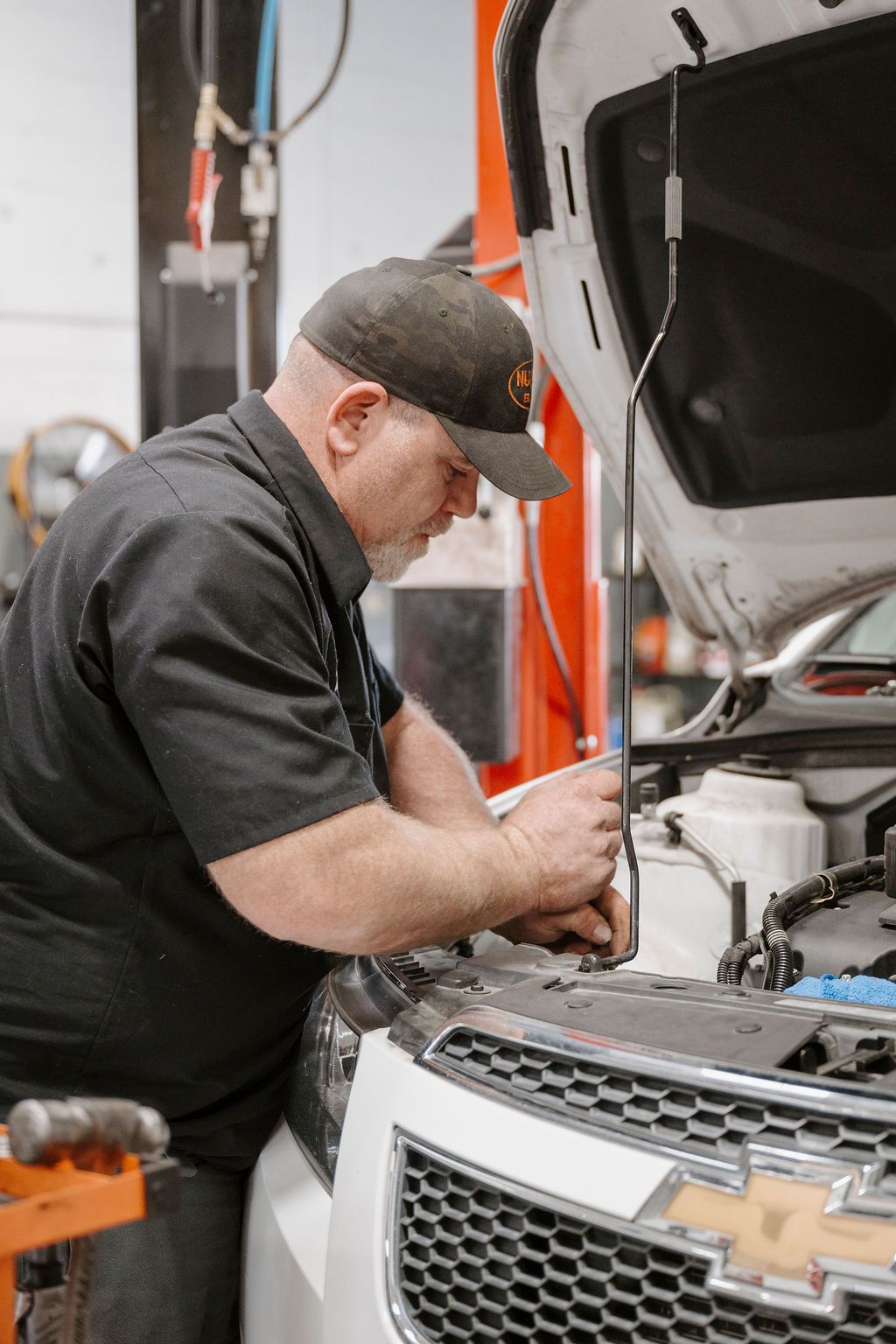 Mechanic working under the hood of a Chevrolet truck in an auto repair shop