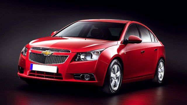 Red Chevrolet sedan on a dark studio background, angled front view
