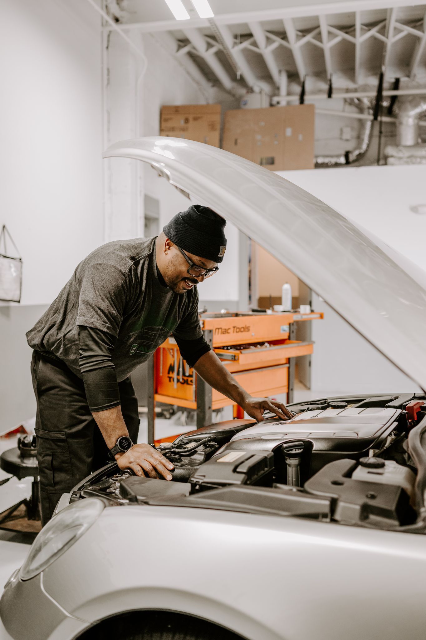 Mechanic working under an open car hood in a garage workshop