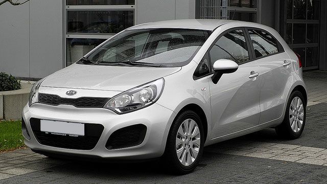 Silver hatchback car parked outdoors in front of a building.