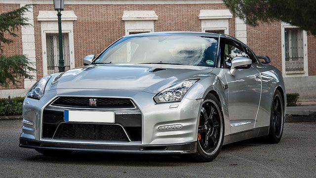 Silver Nissan GT-R parked on a street in front of a brick building