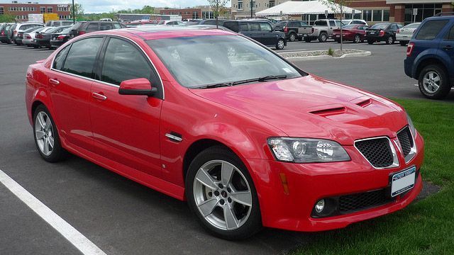 Red sedan parked in a lot, front-left view.