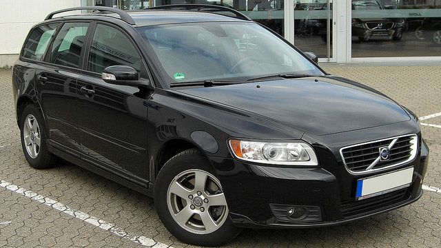 Black Volvo station wagon parked outside a building