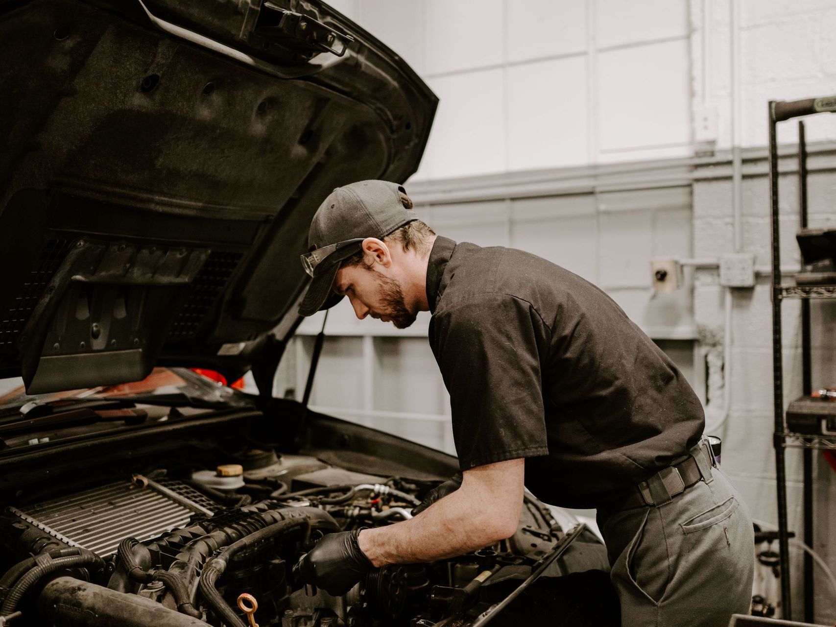 Mechanic inspecting a car engine in a garage with the hood open