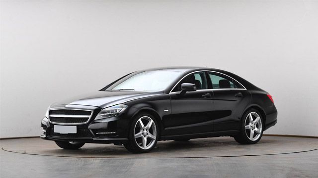 Black sedan car in a studio setting, shown in side view on a light gray background.