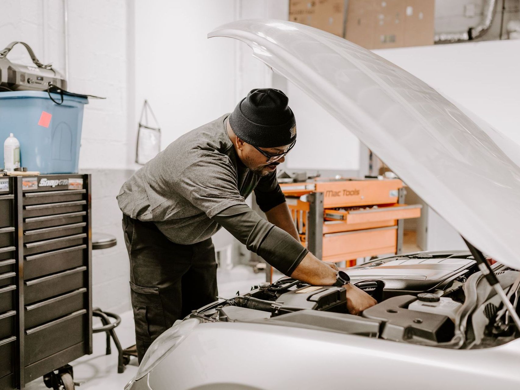 Mechanic working under a raised car hood in an auto repair garage